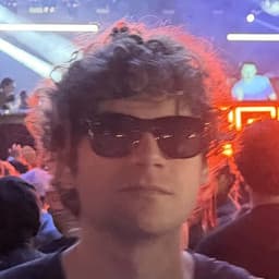 Ethan Marshall, sunglasses on, in concert lighting